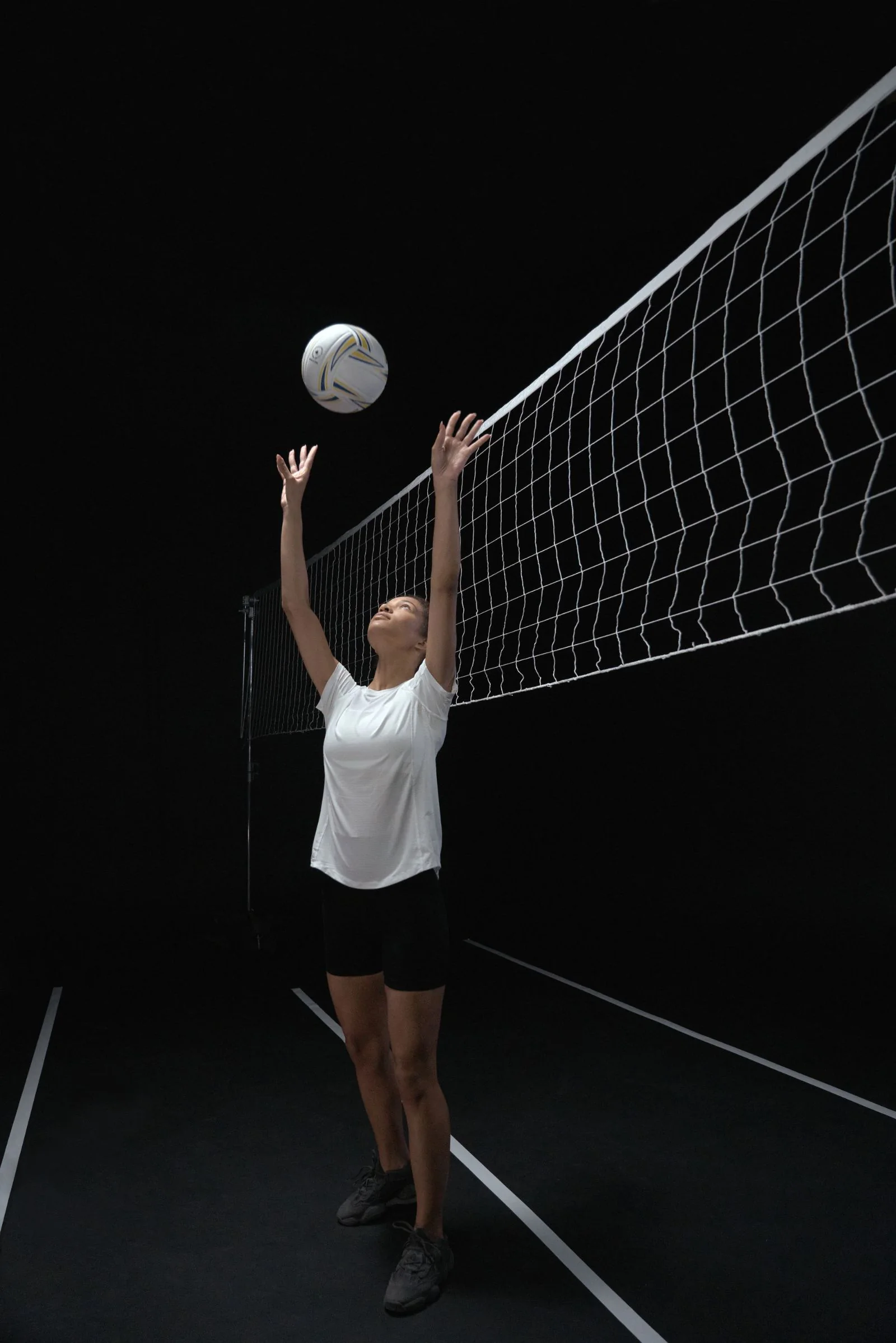 Jugadora de voleibol en la red en un coliseo oscuro
