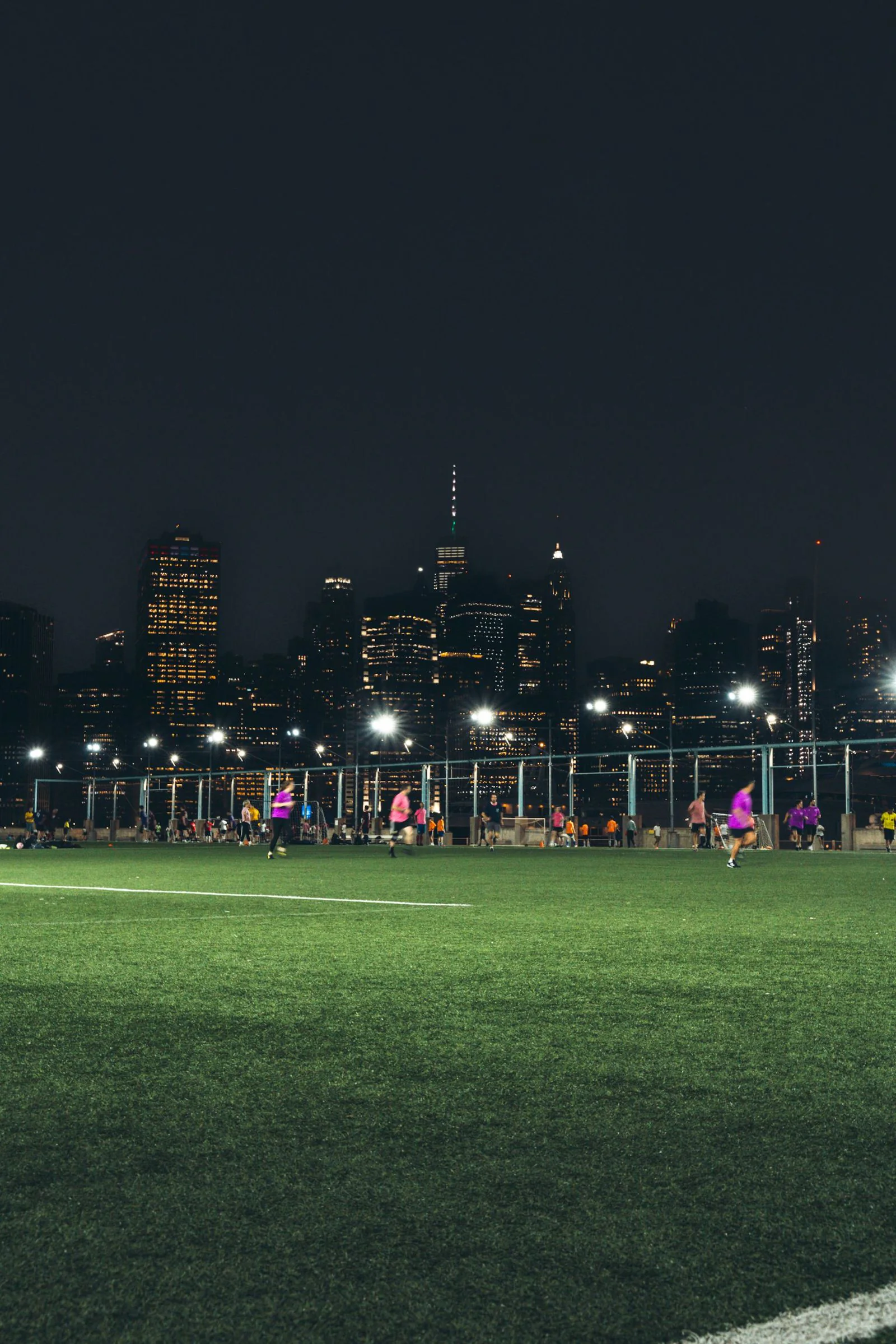 Partido nocturno de fútbol con la ciudad iluminada al fondo