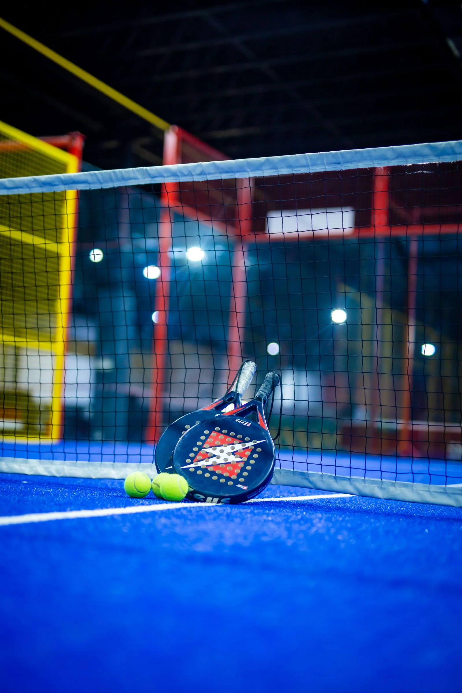 Pista de pádel cubierta con raqueta y pelotas